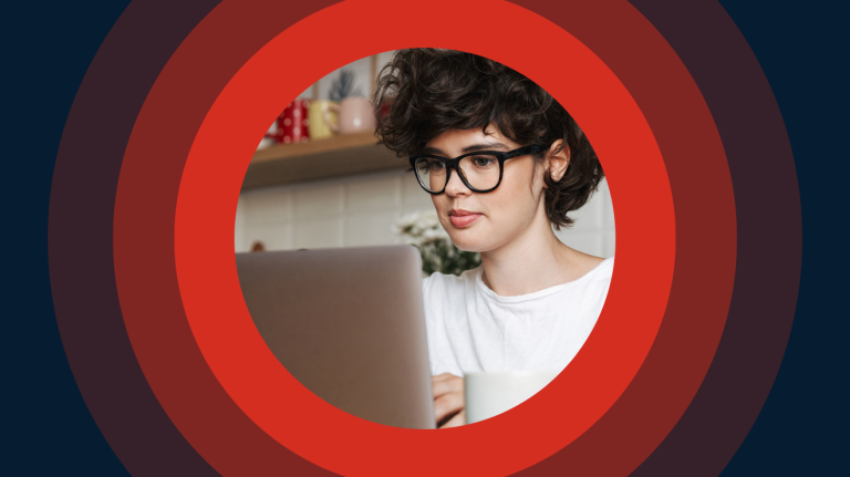 woman with short hair and glasses on a laptop centered on red and maroon concentric rings.