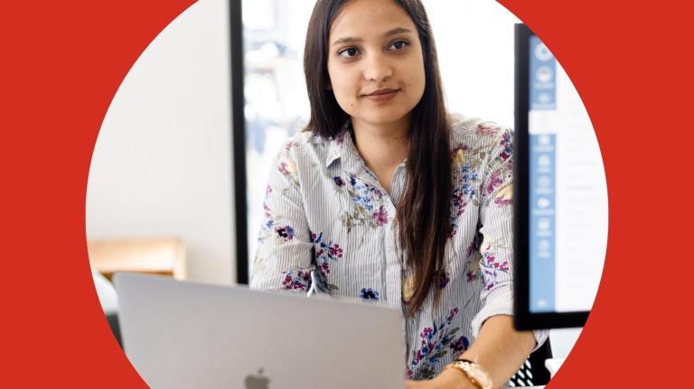 a woman sits at a laptop doing coursework