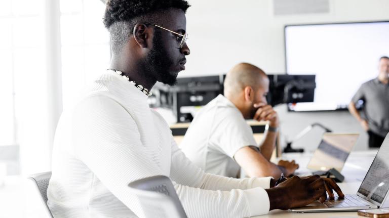 students sit at tables in a higher ed classroom