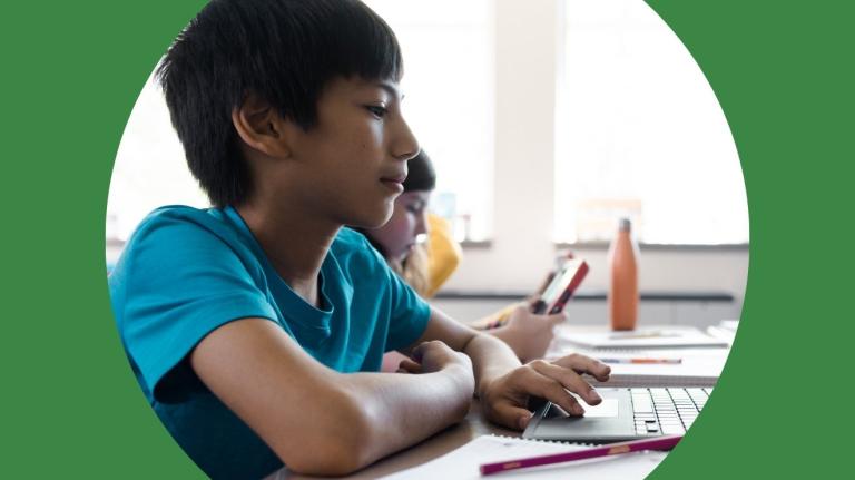 an elementary student takes an assessment on a laptop in a classroom