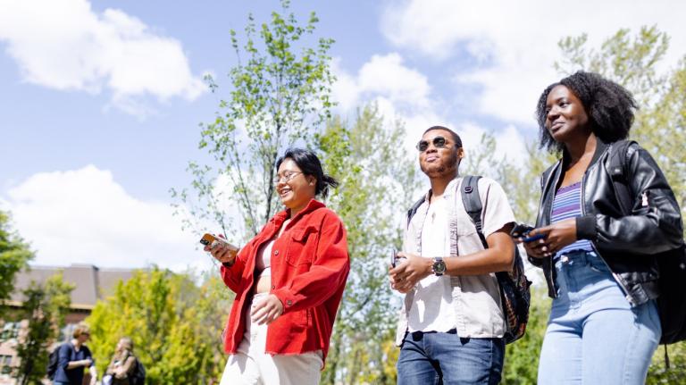 three higher education students walk outside on campus