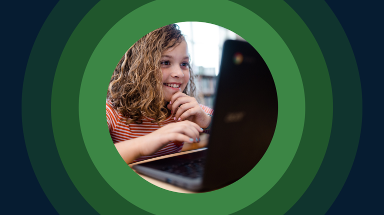 an elementary student sits at a table with a laptop
