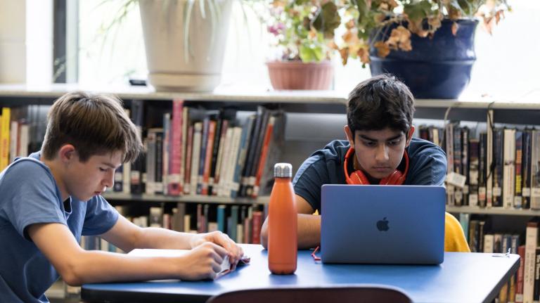 students sit at a table in a school library
