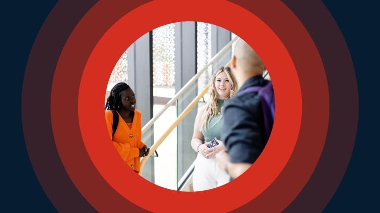 a group of multi-racial college-aged students standing together and talking near a stairway