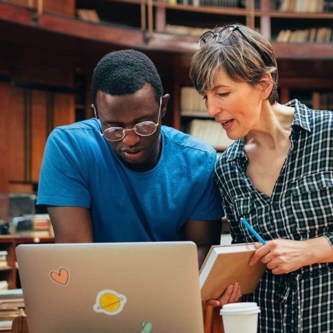 professor showing student work on laptop screen