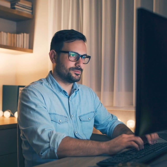 Person with glasses on working at desktop during the evening