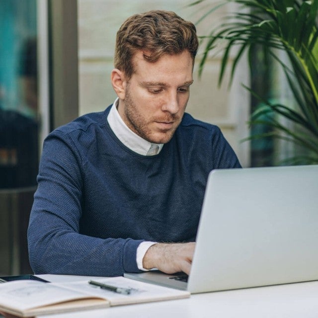 Person sitting at outdoor table working on Canvas