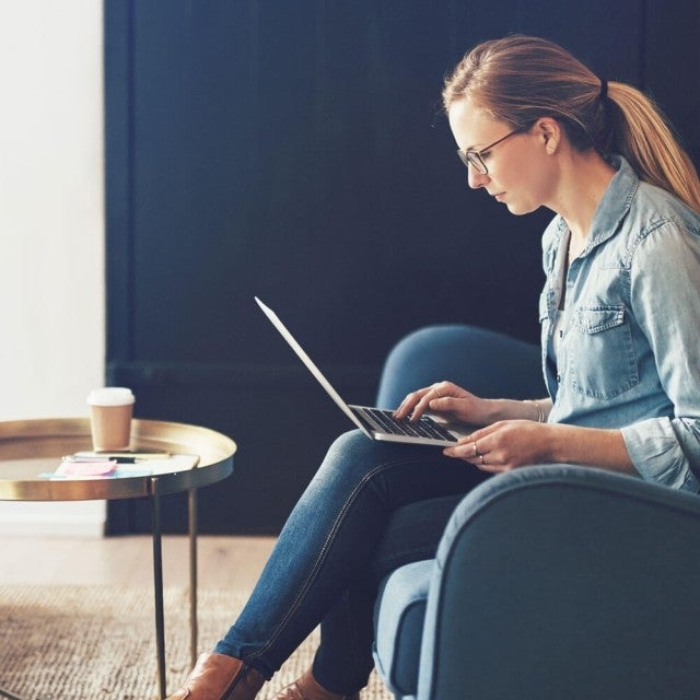 Person sitting in armchair working on laptop