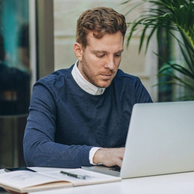 Person working on laptop at table outside