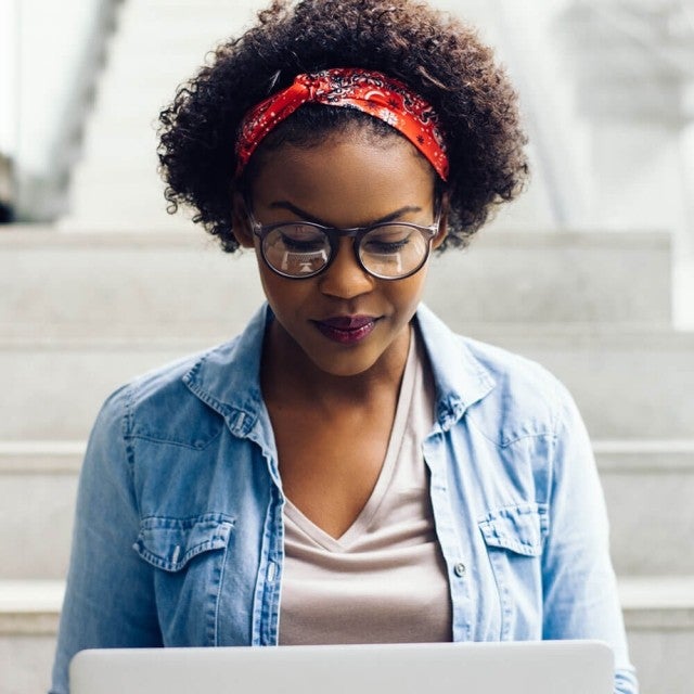 Person sitting outside on steps working on laptop