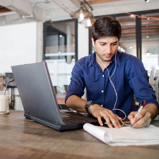 Person with headphones on working on laptop at table