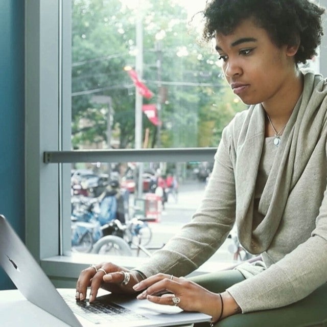 Person working on laptop next to window