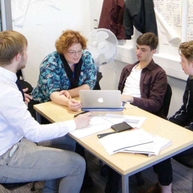 Higher Ed Students working together on laptop in classroom