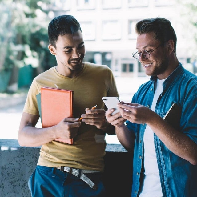 Two students looking at phone outside