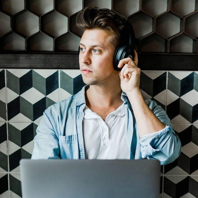 person sitting in cafe with headphones on looking out window