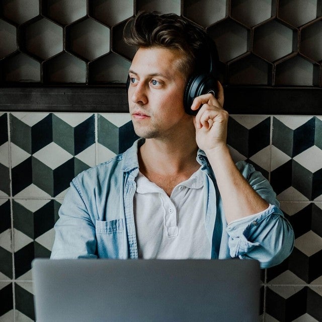 person sitting in cafe with headphones on looking out window