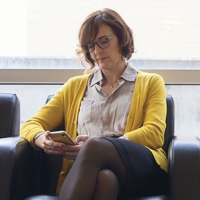 Teacher sitting in chair working on phone