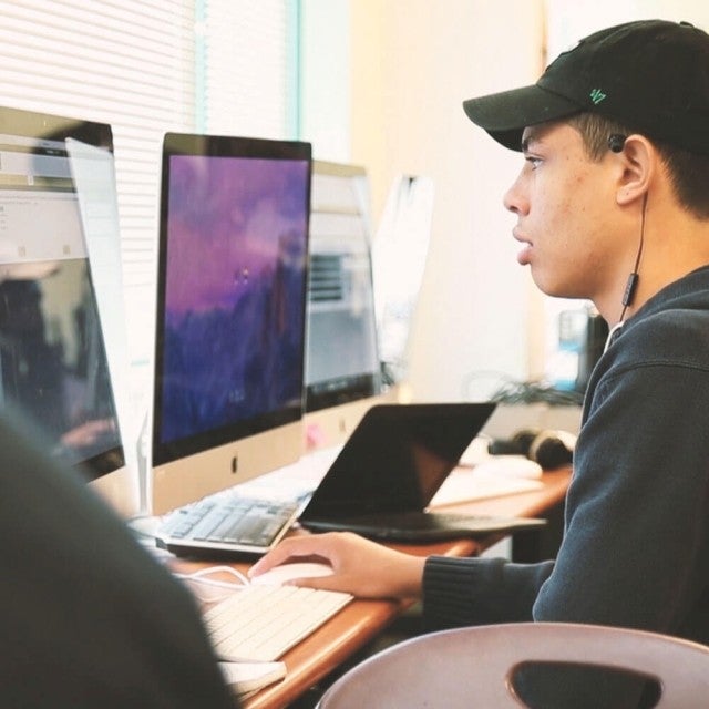 Student with headphones in working on desktop in computer lab