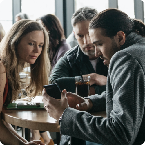 People looking at phone sitting at cafeteria table