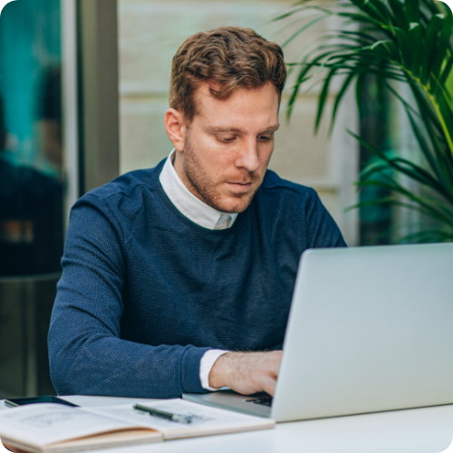 Person working on laptop sitting at table outside