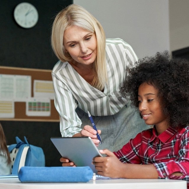Adult talking to student using a tablet