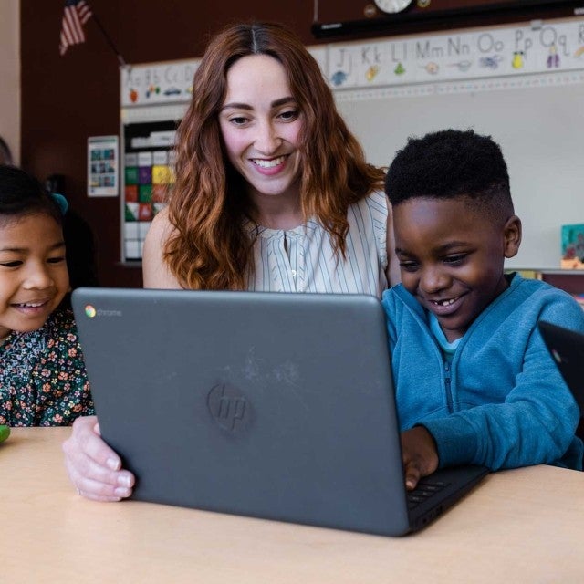 A teacher guiding a student in using the laptop