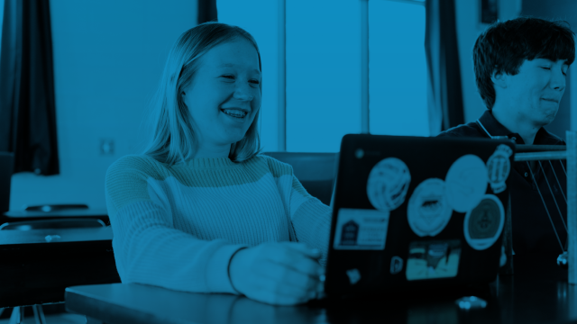 A student smiling while using a laptop
