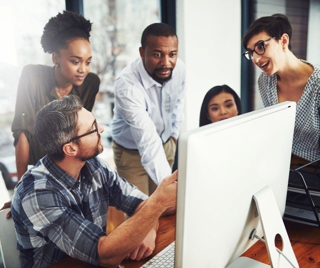 A group of co-workers huddle around a computer
