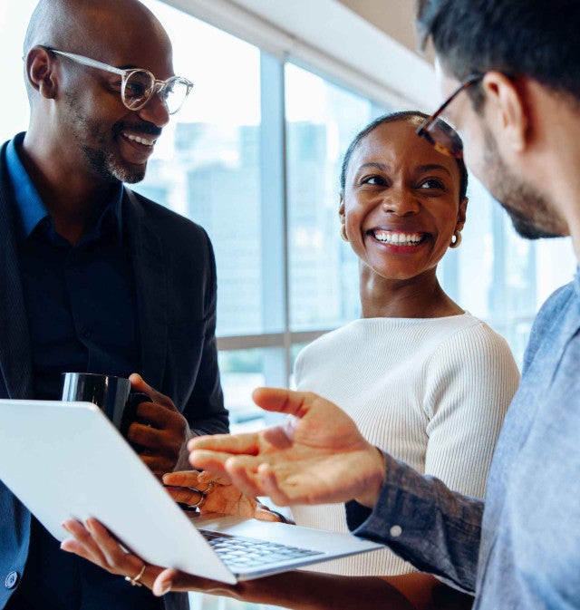 Three professionals working on a laptop