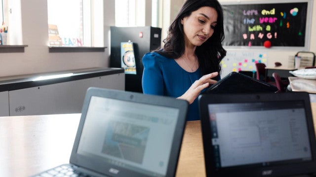 a teacher looks at a laptop in her classroom