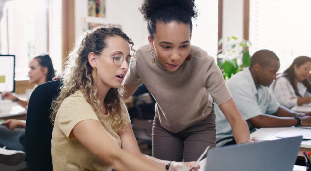 A teacher helping a student on a laptop