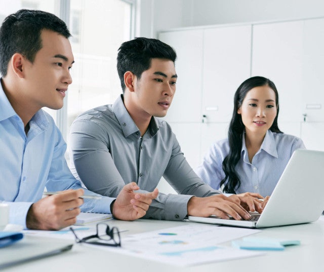 Three professionals working on a laptop