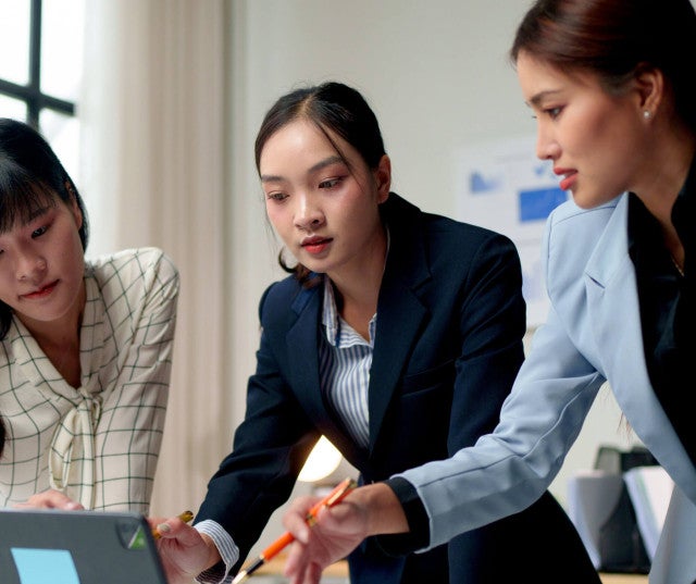 Three co-workers collaborating on a laptop