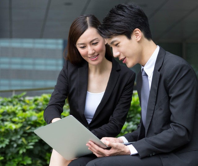 Two co-workers in business suits, looking at a piece of paper